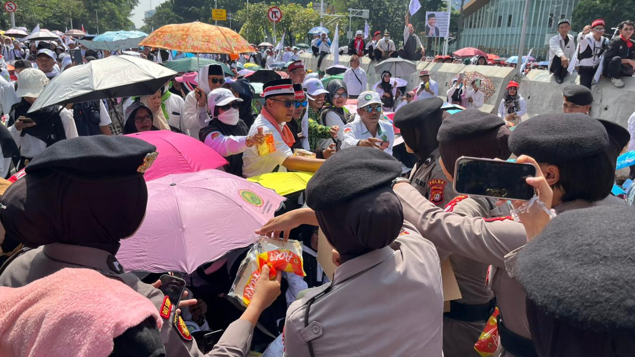 Polisi Bagikan Air Mineral dan Roti kepada Massa Aksi Damai Guru di Silang Selatan Monas